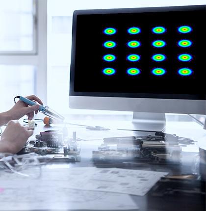 Hand holding a tool in front of a monitor with a coherent optical design